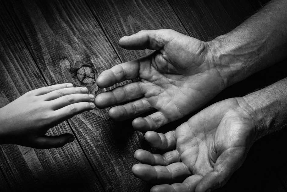 Child hand reaching out to adult hands